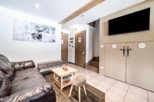a living room with a leather couch and a flat screen tv at Chalet Triplex avec Piscine - Sauna in Samoëns
