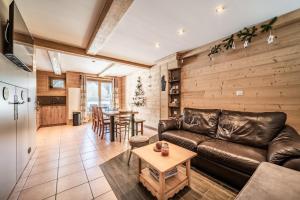 a living room with a leather couch and a table at Chalet Triplex avec Piscine - Sauna in Samoëns