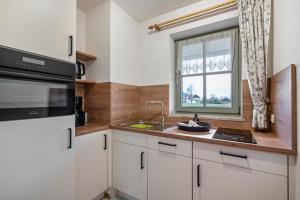 a kitchen with white cabinets and a sink and a window at Fewo Brünnstein - Nr 40 Pool, Sauna in Oberaudorf