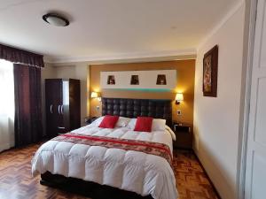 a bedroom with a large bed with two red pillows at Hotel Juan in Arequipa