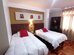 two beds in a hotel room with white and red pillows at Hotel Juan in Arequipa