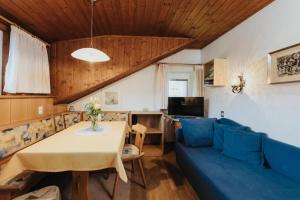 a living room with a blue couch and a table at Unterhauserhof App B in Valdaora
