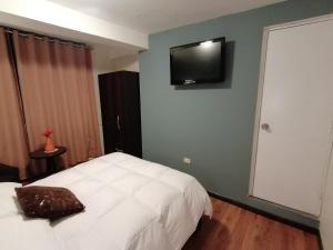 a bedroom with a white bed and a television on the wall at Hotel Juan in Arequipa