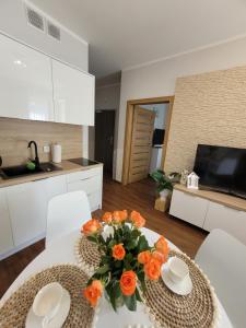a kitchen with a table with orange flowers on it at Apartament Arbuzowy Zachód Słońca in Pobierowo