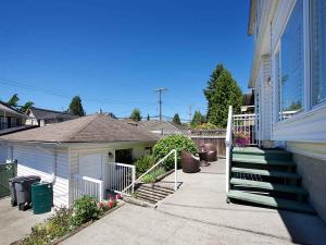 a house with a white gate and stairs in a yard at Marpole Guest House in Vancouver