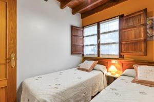 two beds in a room with a window at Orandi in Cangas de Onís