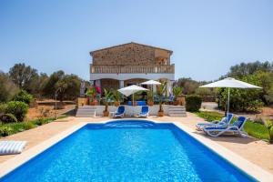 a pool with chairs and umbrellas in front of a house at Oasis del Sol in Llombarts