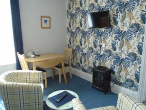 a living room with a table and a tv on a wall at The Florian in Weymouth
