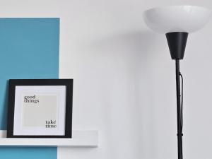 a black floor lamp next to a picture on a shelf at Hey! Central Apartment in Gheorgheni