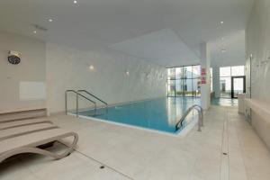a large swimming pool in a building with a pool at Let's Sea Positive Vibe apartment in Gąski