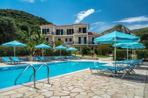 a resort with a swimming pool with blue chairs and umbrellas at Anemona studio A in Kefallonia