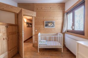 a crib in a room with wooden walls and a window at Appartement style loft Chamonix in Les Houches