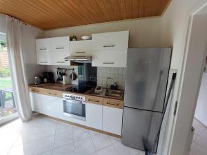 a kitchen with white cabinets and a stainless steel refrigerator at Ferienhaus Dorfidylle in Oberzent +14 photos