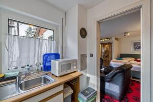 a kitchen with a sink and a microwave and a bedroom at Ferienwohnung Behrens-Reinke in Albstadt +11 photos