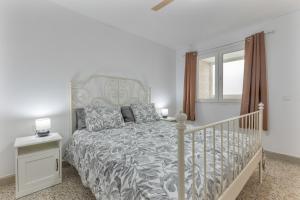 a white bedroom with a bed and a window at Edificio El Baifo Loco - Constantin in Gran Tarajal