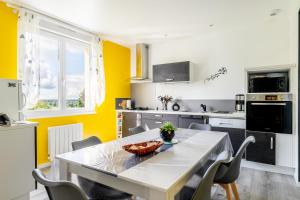 a kitchen with yellow walls and a table and chairs at Maison Ker Morin La Gacilly in La Gacilly