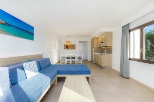 a living room with a blue couch and a kitchen at Apartamento Aquamarina 7 in Cala Ferrera