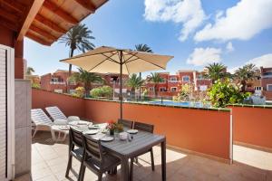 a patio with a table and chairs and an umbrella at Little Dunes in Corralejo