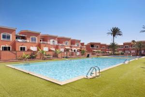a large swimming pool in front of some apartments at Little Dunes in Corralejo