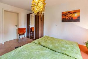 a bedroom with a green bed and a chandelier at Ferienwohnung Im Holzhaus in Donaueschingen