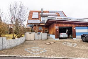 a house with a garage with a car parked in it at Ferienwohnung Im Holzhaus in Donaueschingen
