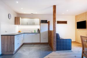 a kitchen with white cabinets and a blue chair at Mittnackerhof Apartment Kamille in Sarntal +19 photos