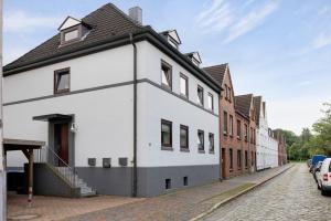 a white building with a black roof on a street at Sabines Ferienwohnung in Glückstadt