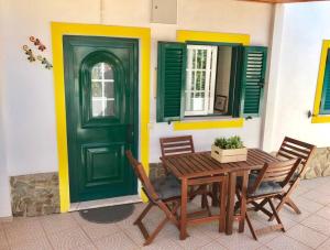 a green door and a table and chairs in front of a house at Casa Sagres in Vila do Bispo