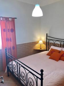 a bedroom with a black bed with orange pillows at Casa Sagres in Vila do Bispo