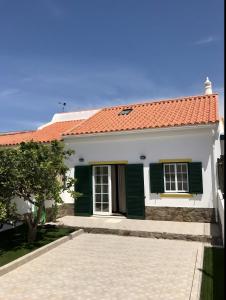 a white house with green shutters on it at Casa Sagres in Vila do Bispo