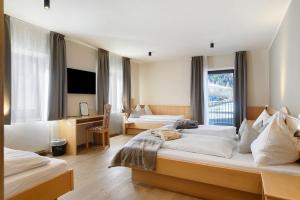 ein Hotelzimmer mit zwei Betten und einem Schreibtisch in der Unterkunft Hotel Murrer relaxe.nature.gusto in Sarntal
