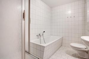 a white bathroom with a tub and a toilet at Haus Seeadler Wohnung 13 in Koserow