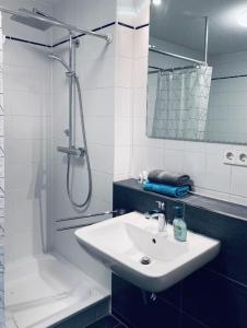 ein weißes Badezimmer mit Waschbecken und Dusche in der Unterkunft Seewest in Singen