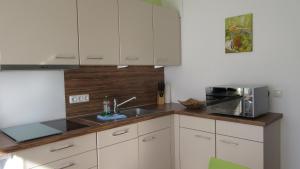 a kitchen with white cabinets and a sink and a microwave at Ferienwohnung Stella Fiante in Juliusruh +12 photos