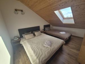 a attic bedroom with two beds and a window at Apartamenty pod Orzechem in Kościerzyna