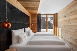 two beds in a room with wooden walls at Chalet-Suite Wasser in Selva dei Molini