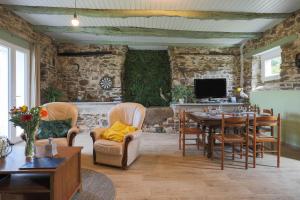 a living room with a table and chairs and a tv at L'abreuvoir du Leffo in Allineuc
