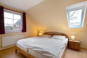 a bedroom with a large bed with two windows at Ferienwohnung Nico in Langballig