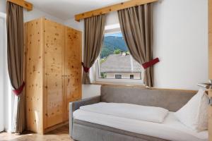 a bedroom with a couch and a large window at Hotel Residence Olympia Sarntal in Sarntal +83 photos