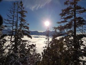 a view of a snowy mountain with the sun in the sky at Chalet Falkenstein in Garmisch-Partenkirchen