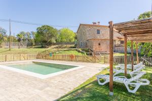 a house with a swimming pool and two white chairs at Can Malràs in Massanas