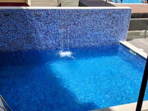 a large blue swimming pool with a water fountain at Ap Calafell piscina, climatizado,pk in Calafell
