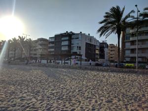 a sandy beach with some buildings and palm trees at Ap Calafell piscina, climatizado,pk in Calafell