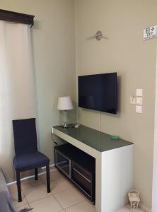 a room with a desk with a tv and a chair at Anemi Leros Apartments 2 in Panteli