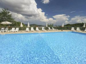a large swimming pool with chairs and umbrellas at Mono Le Lecce 53 Iris in Capoliveri