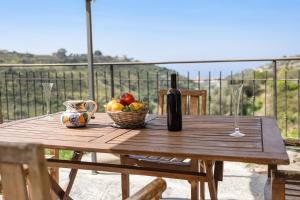 a wooden table with a basket of fruit and a bottle of wine at Pelagos in Pompeiana