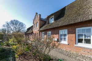 an old brick house with a thatched roof at Hus Tingeltut Gerd Clausen in Pellworm