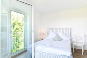 a white bedroom with a bed and a large mirror at Dinkelbach Feriendomicil 2 D in Lindau-Bodolz