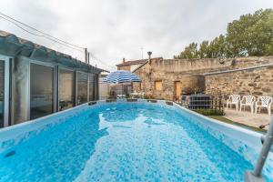 a swimming pool with an umbrella next to a building at Amontes Rural in Nestar