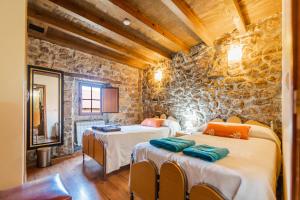 a room with two beds and a stone wall at Amontes Rural in Nestar +31 photos